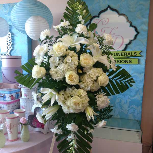 White floral standing spray on an easel with lilies and roses