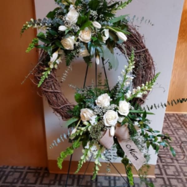 Two white floral wreath arrangements on black stands