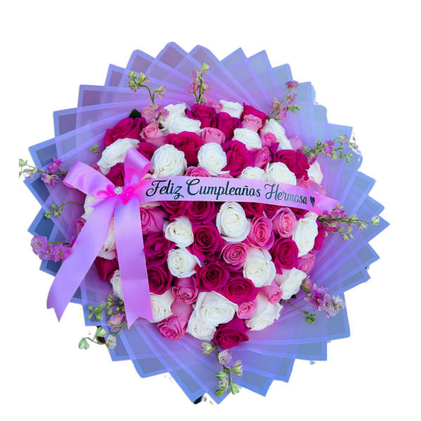 Large round bouquet of pink and white roses wrapped in purple paper with a Spanish birthday ribbon and pink bow.