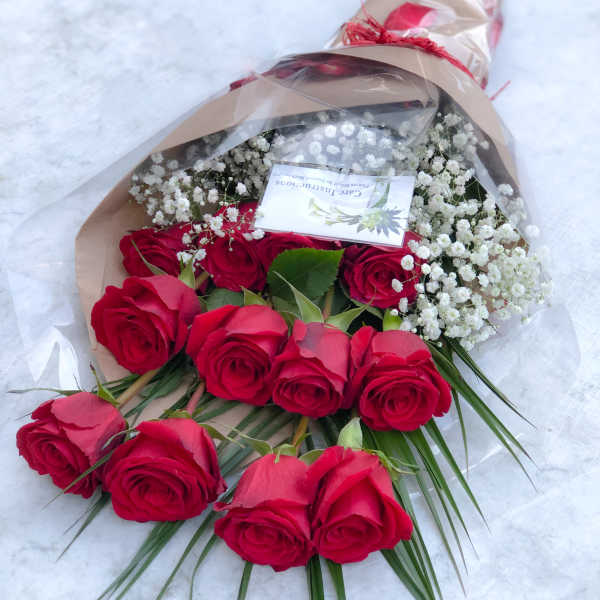 Bouquet of red roses with white baby's breath in brown paper
