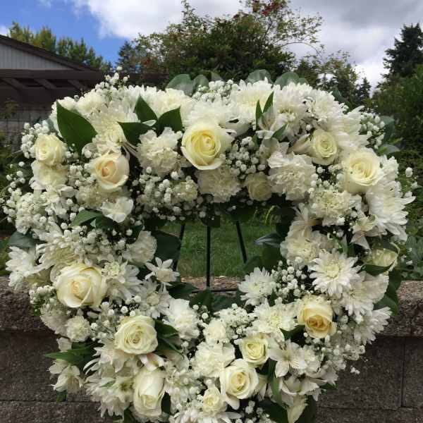 White floral heart wreath with roses and daisies on an easel