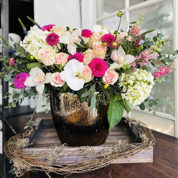 Pink roses and white orchids in a dark vase with white hydrangeas