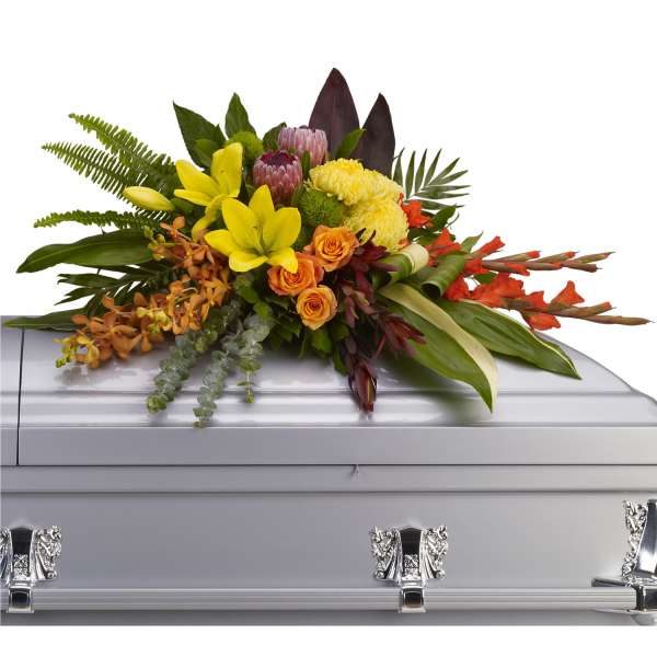 Colorful floral spray arranged on top of a silver casket