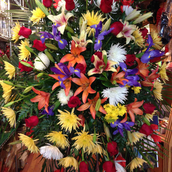 Large mixed floral spray with red roses, lilies, and yellow and white blooms