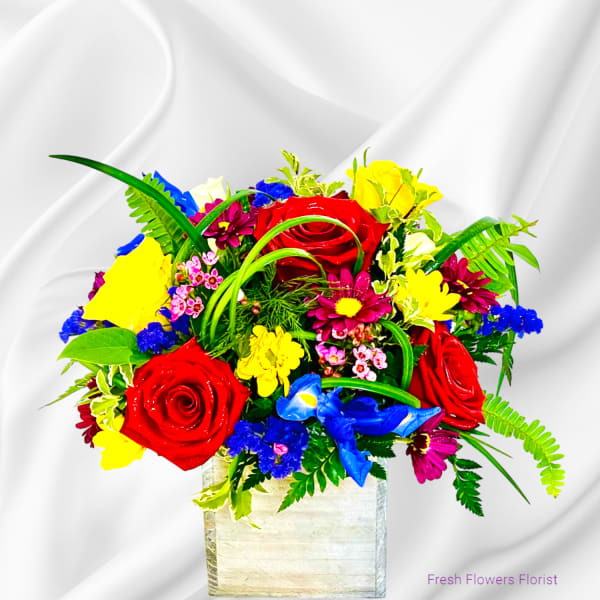 Bright mixed bouquet of roses and daisies in a square vase