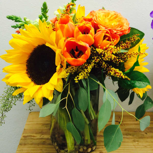 Sunflower and orange tulip bouquet in a glass vase