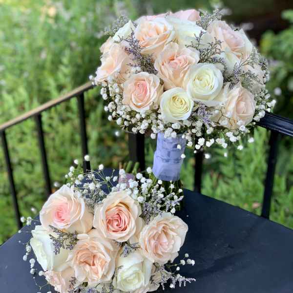 Two pastel rose bouquets with baby's breath on a dark table
