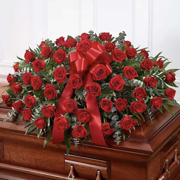 Red rose casket spray with a large red ribbon bow