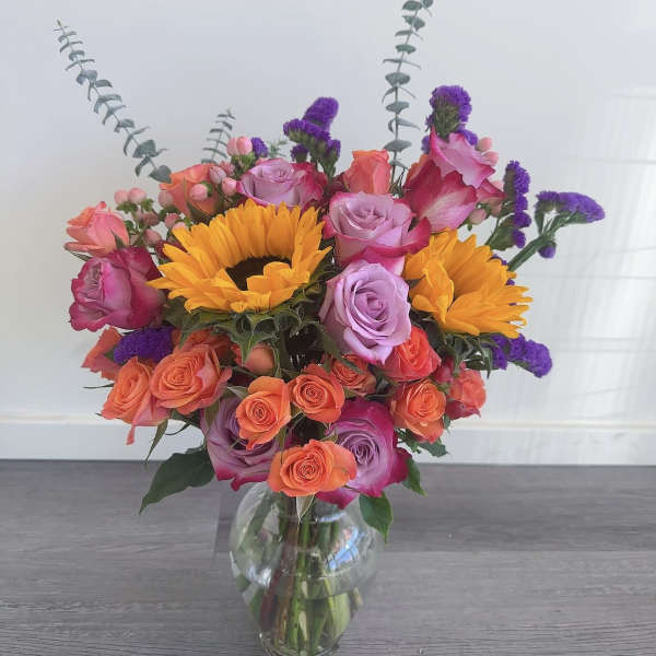 Mixed bouquet of roses and sunflowers in a clear glass vase
