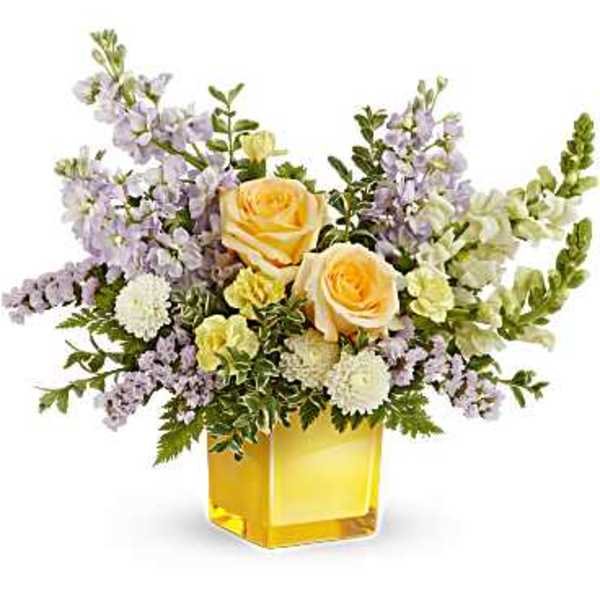 Yellow roses and lavender flowers in a square glass vase