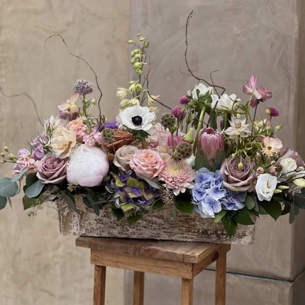 Mixed pastel floral arrangement in a rustic rectangular container
