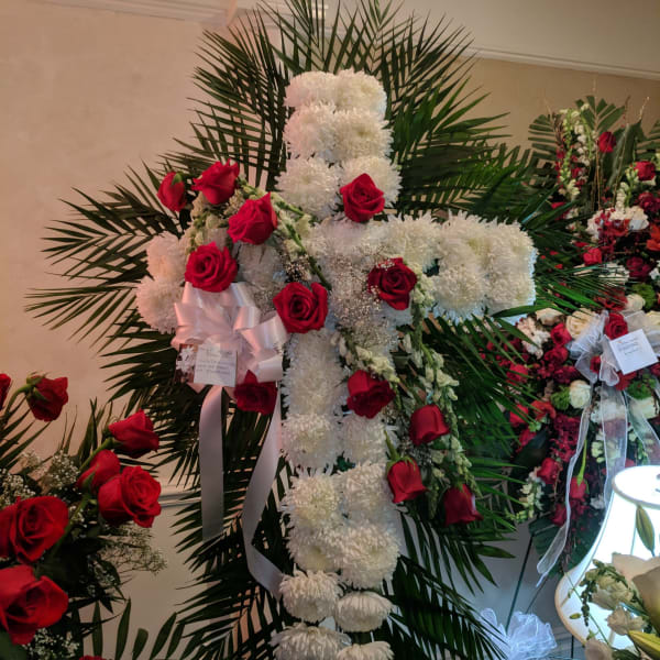 Standing floral cross of white chrysanthemums and red roses with palm fronds