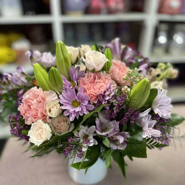 Mixed pink and lavender flowers arranged in a white vase