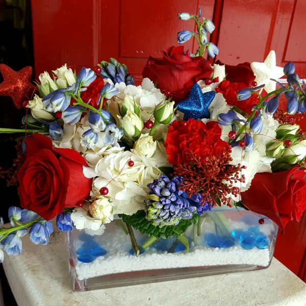 Red roses and white flowers arranged in a clear rectangular vase