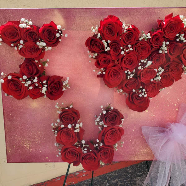 Red rose heart display on a pink board with a tulle bow