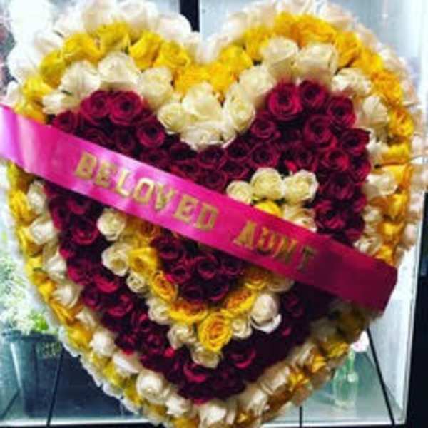 Heart-shaped rose arrangement with a pink ribbon reading "BELOVED AUNT"