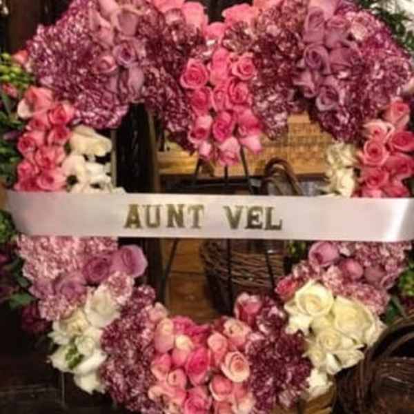 Pink and purple floral funeral wreath with a white ribbon reading AUNT VEL