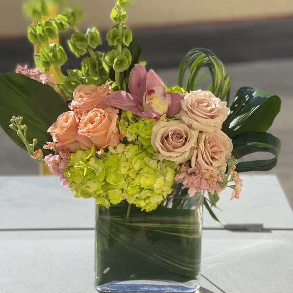 Pink roses and green hydrangeas in a square glass vase
