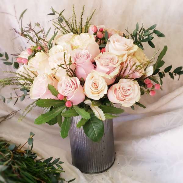 Pink and white roses arranged in a tall metal vase
