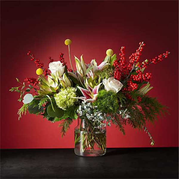 Mixed floral arrangement in a clear glass vase with red berry branches