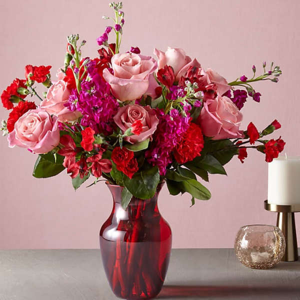 Pink roses and red carnations in a red glass vase