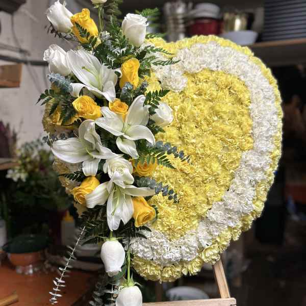 Heart-shaped floral wreath with white lilies and yellow roses