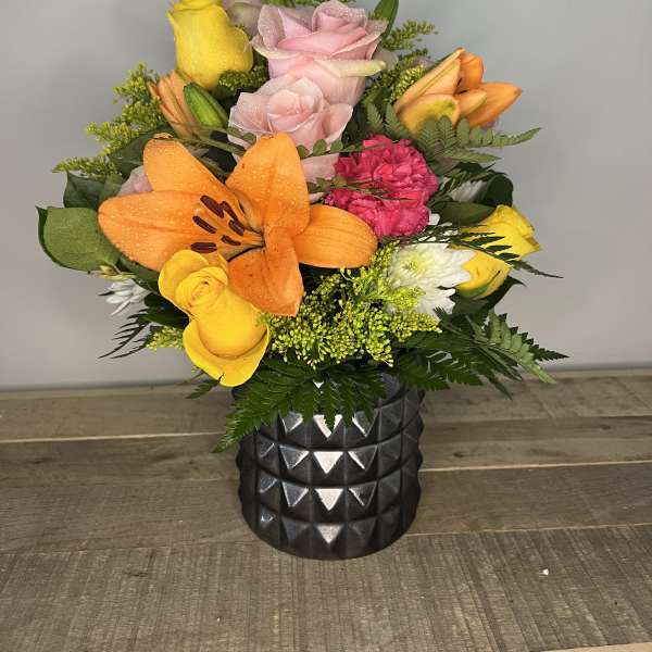 Mixed bouquet with roses, lilies, and carnations in a black vase