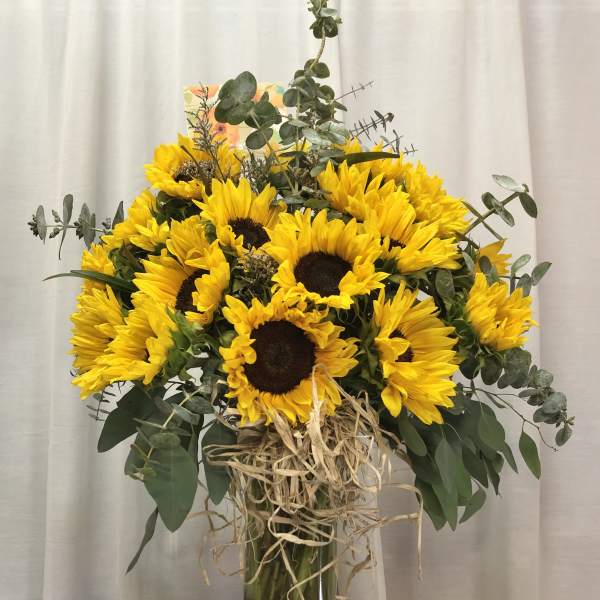 Sunflower bouquet in a glass vase with eucalyptus and raffia wrap