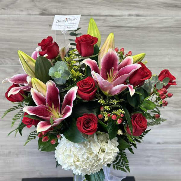 Bouquet of red roses, pink lilies, and white hydrangea in a glass vase