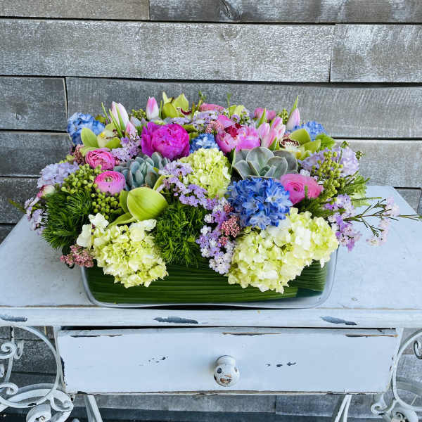 Colorful mixed flower arrangement in a rectangular glass vase