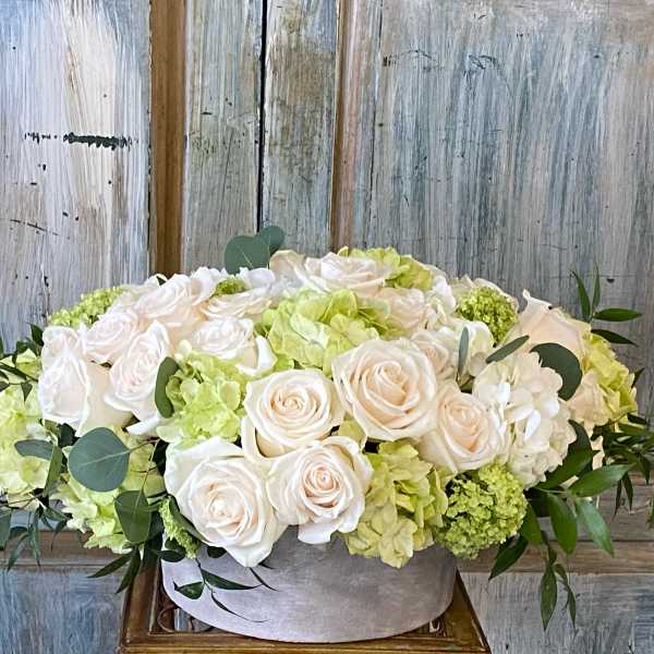 Cream roses and pale green hydrangeas in a low gray box