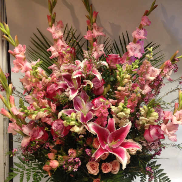 Large pink floral arrangement with lilies, roses, and tall gladiolus