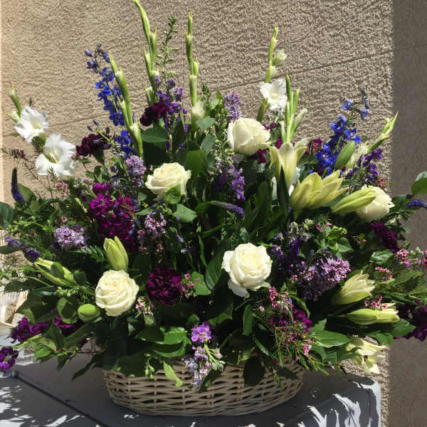 Large basket arrangement of white roses, lilies, and purple flowers