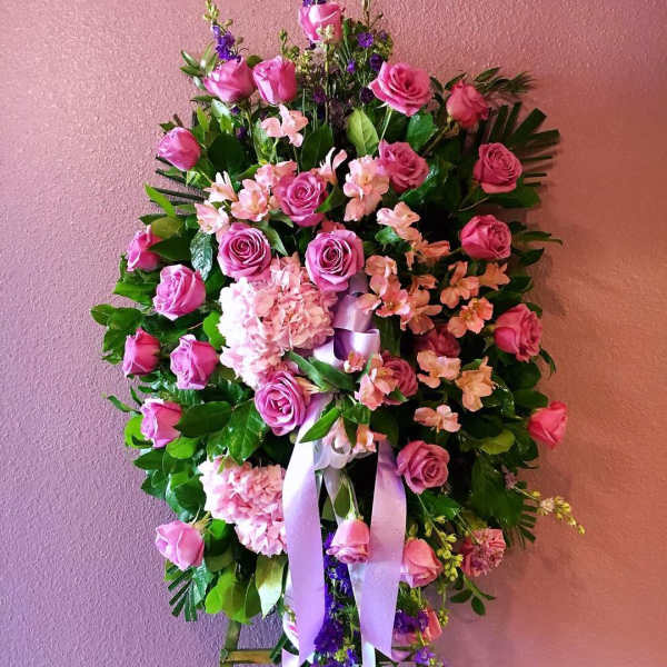 Pink rose funeral spray with ribbons on an easel