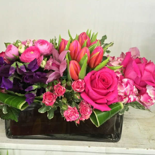 Pink and purple mixed flower arrangement in a black rectangular vase