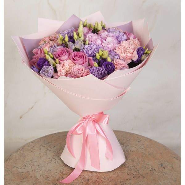 Pink and lavender bouquet wrapped in pale pink paper with a ribbon