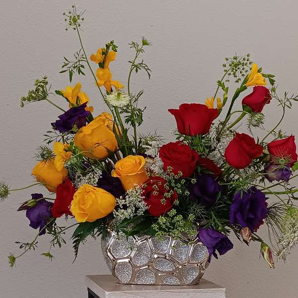 Bouquet of red, yellow, and purple roses in a silver vase