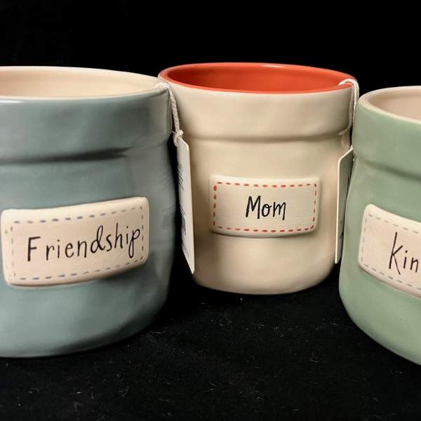 Three pastel ceramic candle jars labeled Friendship, Mom, and Kind