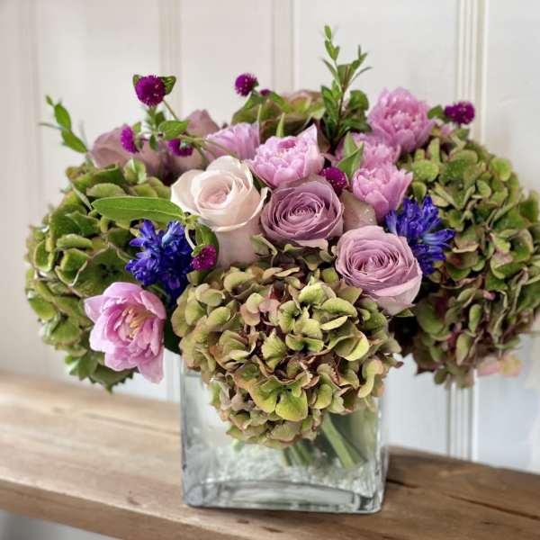 Pink and purple bouquet in a square glass vase