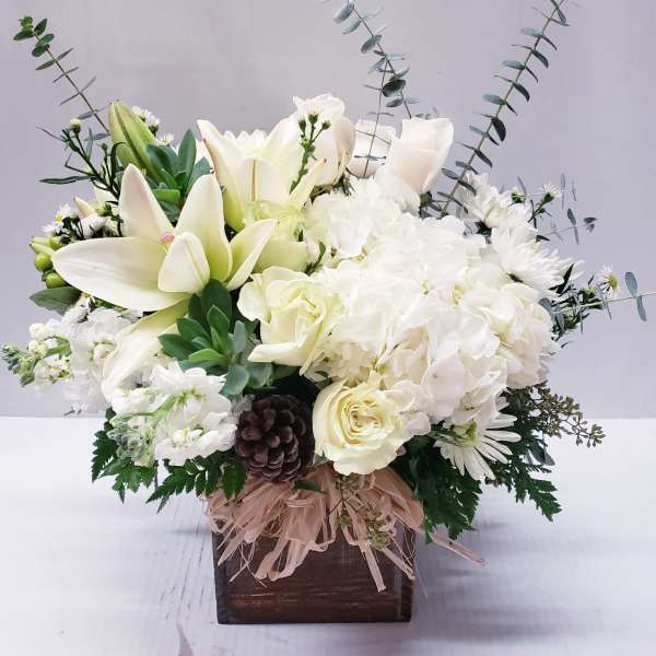 White floral arrangement with lilies, roses, and hydrangeas in a wooden box