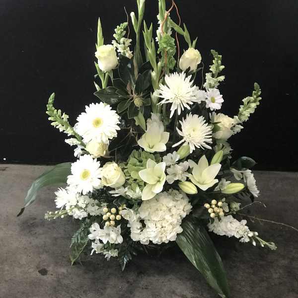 White floral arrangement with daisies, lilies, and roses in a low display