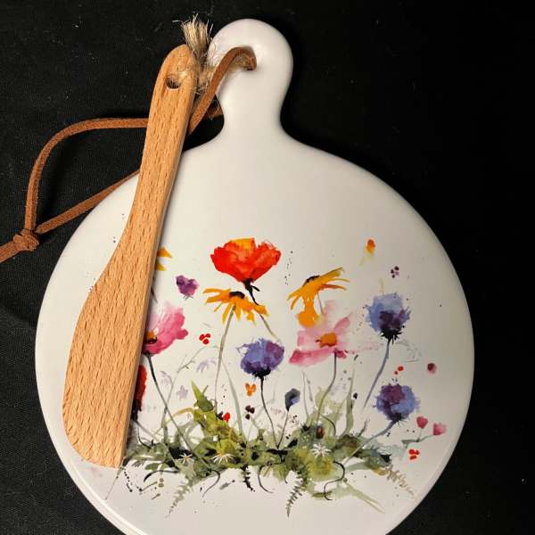 Round white ornament with painted wildflowers and a wooden spoon tied on