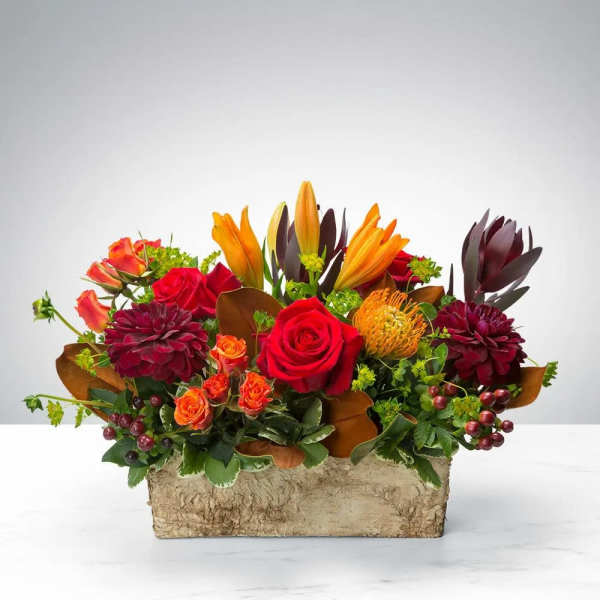 Mixed bouquet of red roses and orange lilies in a rectangular container