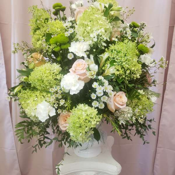 Large bouquet of pale roses, white blooms, and green flowers in a white vase