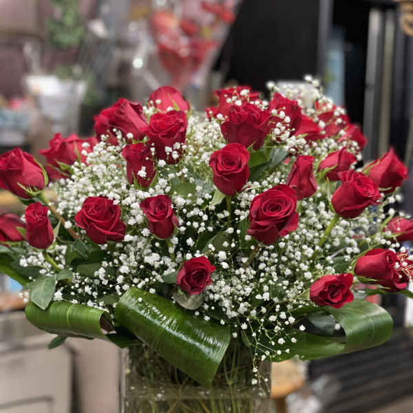 Red roses arranged in a clear glass vase with white baby's breath