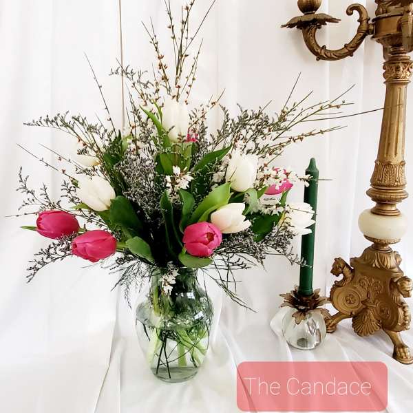 Pink and white tulips in a glass vase with airy filler