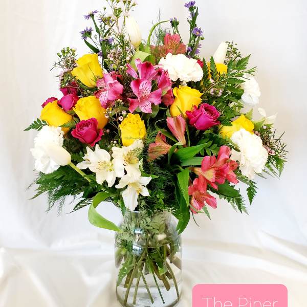 Mixed bouquet of pink, yellow, and white flowers in a glass vase