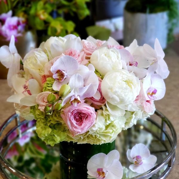 Pink and white bouquet with orchids, roses, peonies, and hydrangeas in a dark vase