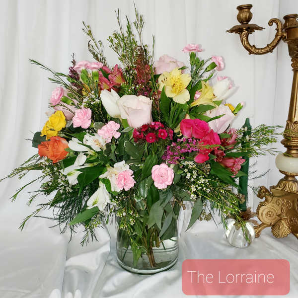 Mixed bouquet in a clear glass vase with pink, white, yellow, and orange flowers