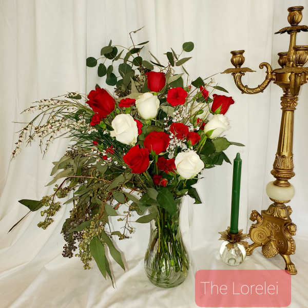 Red and white roses in a clear glass vase with greenery